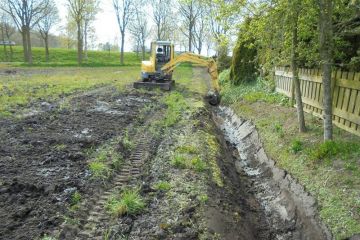 Graafmachine aan het werk in een sloot langs bomen en een schutting bij singelonderhoud.