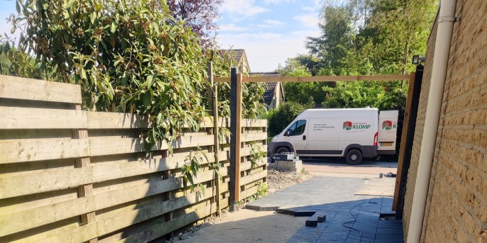 Achtertuin met plant die over de schutting hangt